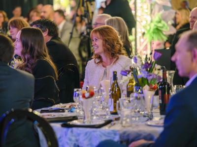 A smiling woman sitting at a banquet table and looking to the left